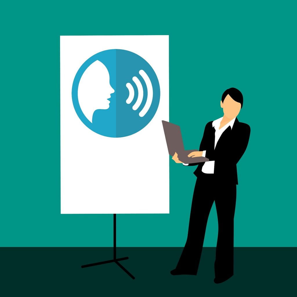 A cartoon image of a person in a black suit holding a laptop in front of a presentation screen with an graphic of a talking head.